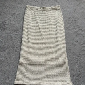 Beige stickad långkjol från Pieces - Beige stickad långkjol från Pieces i mjukt material. Kjolen har en rak passform och är ribbstickad för en snygg struktur. Perfekt att styla med en enkel topp eller oversized tröja för en chill look. Aldrig använd 