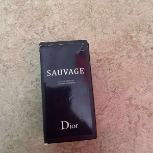 Dior Sauvage Eau de Parfum 100ml - Dior Sauvage Eau de Parfum i 100ml flaska. Parfymen kommer i en elegant, mörkblå kartong med vit text och klassisk Dior-logga. En ikonisk doft med maskulin och fräsch känsla, perfekt för dig som gillar exklusiva och moderna parfymer.