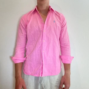 Rosa Ralph Lauren skjorta  - Rosa Ralph Lauren skjorta || storlek XS|| Mitt pris 449kr || Skjortan är i okej skick, slitage och fläckar förekommer (se bilder) Modellen på bilden är 170cm och väger 62kg || Tveka inte på att höra av dig vid frågor eller funderingar 