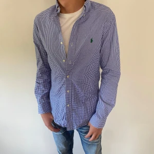 Blårutig skjorta från Ralph Lauren - Klassisk blårutig skjorta från Ralph Lauren med button-down krage och grön broderad logga på bröstet. Skriv vid minsta fundering!