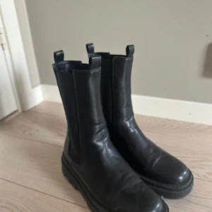 Svarta boots - Snygga svarta boots i skinn med en robust sula och dragflikar upptill. Perfekta för en stilren look.