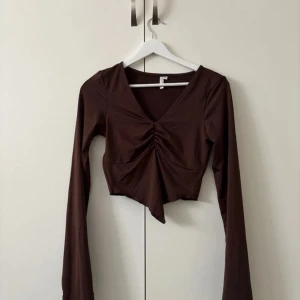 Brun långärmad topp från NLY Trend - Snygg brun långärmad topp från NLY Trend med v-ringning och rynkdetalj framtill. Perfekt för en stilren look.