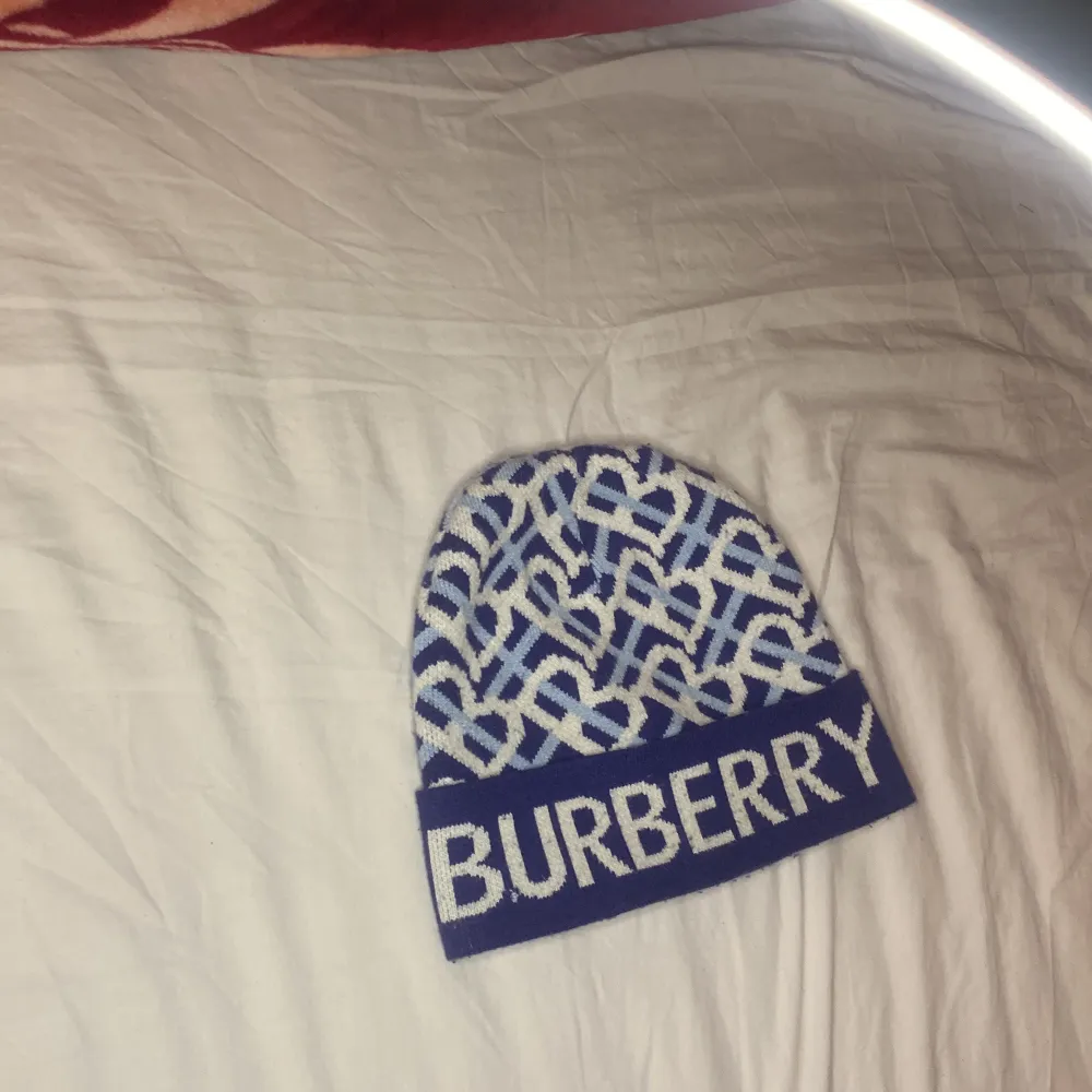 Snygg blå och vit mössa från Burberry med ett unikt mönster och logotyp framtill. Perfekt för att hålla stilen i kallare väder.. Asusteet.