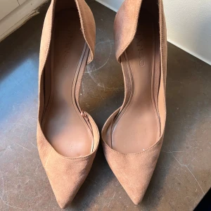 Bruna mockapumps - Snygga bruna pumps i mocka med spetsig tå och elegant klack. Perfekta för att ge en stilren touch till din outfit.
