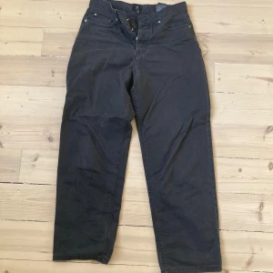 Svarta byxor från H&M - Säljer ett par svarta byxor från H&M i loose fit. Byxorna har en klassisk design med knappar och dragkedja framtill. Perfekta för en avslappnad stil.