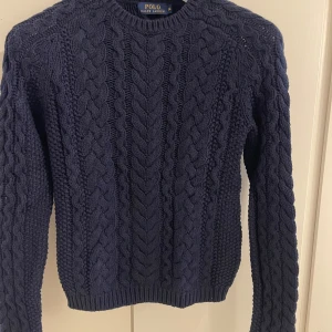 Mörkblå kabelstickad tröja från Polo Ralph Lauren, obs helt Nya! St M & L - Säljer 2 snygga mörkblå kabelstickad tröjor från Polo Ralph Lauren. Tröjan har ett klassiskt flätmönster och långa ärmar, perfekt för kyliga dagar. Den är både stilren och bekväm, ett måste i garderoben! 💙st M & L finnes, från butiken Jackie, 