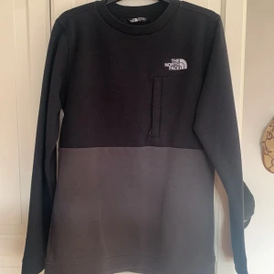 Svart och grå tröja från The North Face - Säljer en stickad svart och grå tröja från The North Face. Tröjan är relativt bra skick haft den ett tag men inga deflekter.