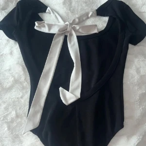 Svart body  - Söt svart body med ett vitt knytband i ryggen från Bershka🖤 Säljer då den inte kommer till användning. Storlek XS men passar S också🖤