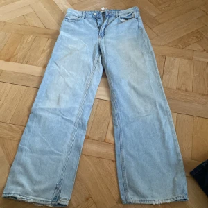 Ljusblå jeansbyxor från H&M - Säljer ett par ljusblå jeansbyxor från H&M med en avslappnad passform. Byxorna är näst intill oanvända, lite stor i midjan och har inget band att dra åt i, lite gula på ben  och bakfickorna men annars i bra skick, Frågor? Kontakta mig på Plick!