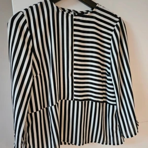 Chiffongblus Gina Tricot  - Svart och vit randig chiffongblus med trekvartsärmar. Från Gina tricot storlek 34. Lätt oversize. Använd en gång, I mycket fint skick.