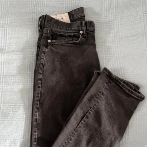 Svarta slim fit jeans från H&M - Snygga svarta slim fit jeans från H&M. Perfekta för en stilren look med klassisk design och bekväm passform. De har en dragkedja och knappar framtill.