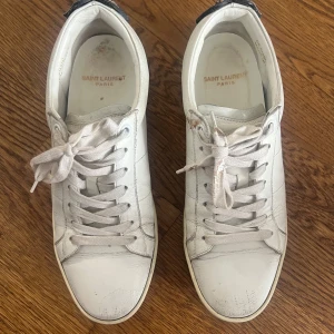 Yves Saint Laurent vita sneakers med zebra-detalj! - Snygga vita sneakers från Saint Laurent med coola zebra-mönstrade läppar och metallnitar på hälen. Ganska använda. Allt går att tvätta av, jag är bara ganska lat. DE ÄR ÄKTA 