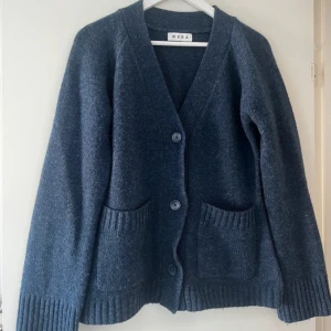 Mörkblå kofta från Wera med fickor - Säljer en mörkblå kofta från Wera med två stora fickor framtill och ribbade muddar vid ärmslut och nederkant. 