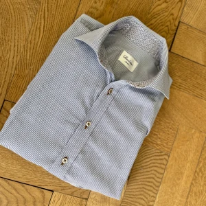 Stenströms skjorta - Snygg blå och vit randig skjorta från Stenströms i slim fit. Skjortan har klassisk krage med mönstrad insida, långa ärmar och knappar framtill. Tillverkad i mjuk bomull som känns skön mot huden. Perfekt för dig som gillar stilrena detaljer. Pris är inte hugget i sten. Hesitera inte att fråga vid minsta beundran.