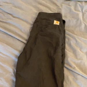 Svarta Carhartt loose byxor - Säljer ett par svarta cargopants från Carhartt med klassisk logga på fickan. Byxorna har raka ben och flera praktiska fickor. Materialet är slitstark bomull som passar perfekt för dig som gillar streetwear och utility-stil. Använda 2-3 gångar