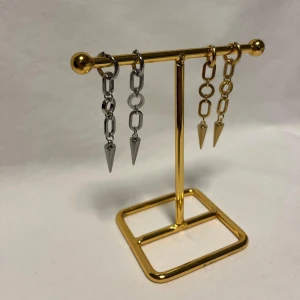Chunky kedjeörhängen med spikes - Två par coola örhängen med chunky kedjor och spetsiga spikes i metall. Ena paret är i silverfärg och det andra i guld, båda har en edgy vibe och passar perfekt till streetstyle. Säljs utan märke, materialet är metall och designen är riktigt trendig.