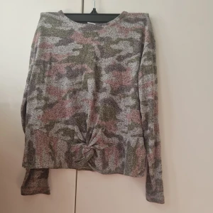 Camouflage-mönstrad tröja från Lindex - Säljer en långärmad tröja från Lindex med camouflage-mönster i grått, grönt och rosa. Det här var en av mina favorit tröjor när jag var mindre då den är väldigt bekväm. Storlek 134/140.