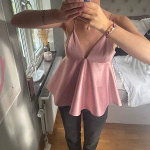 Ljusrosa omlott blus med v-ringning - Supersöt ljusrosa topp. Materialet har en lätt glans och känns mjukt mot huden.
