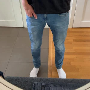Reserverade - Snygga ljusblå jeans från Replay med klassisk femficksdesign och bruna läderpatch bak. Jeansen har slim passform, raka ben och coola slitningar framtill. Materialet är mjukt jeans med stretch för extra komfort. Perfekt för dig som gillar en modern och avslappnad stil.
