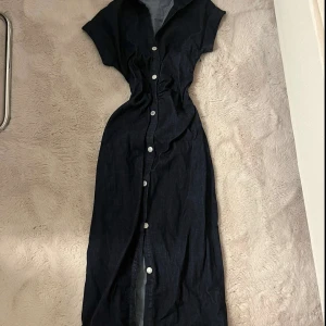 Zara jeans klänning - Snygg mörkblå långklänning med korta ärmar och vit knappstängning hela vägen framtill. Klänningen har en figurnära passform och krage, endast testad