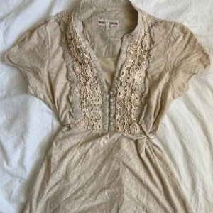 Babydoll tröja  - Så fin kortärmad babydoll tröja med spets, knappar och ett band som knyts under bysten för en perfekt passform💕 I en beige färg, något ljusare i verkligheten då färgen var svår att fånga på bild! I fint skick💕