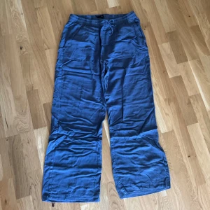 Blå linnebyxor från Lager 157 - Säljer ett par chill blå linnebyxor från Lager 157, modell Denise. De har breda ben, elastisk midja med snörning och två sidofickor. Perfekta för dig som gillar loose fit och vill ha något skönt och luftigt på sommaren.