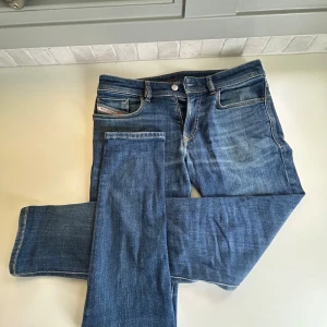 Blå jeans från Diesel W30 - Snygga blå jeans från Diesel med klassisk femficksdesign och diskreta slitningar. Modellen har raka ben och normal passform, med tydliga Diesel Industry-detaljer på fickan. Materialet är mjukt och stretchigt jeans, perfekt för en chill och stilren look.