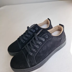 Louboutins svarta - Snygga svarta sneakers i mocka med klassisk rund tå och platt sula. Skorna har svarta snören och en mjuk beige insida. Yttersulan är svart med en cool röd undersida och grafiskt mönster. Perfekta för dig som gillar stilrena och moderna detaljer. Säljer då jag ville testa något annat storlek 43 helt oanvända sökord: louboutins, svarta skor, svarta sneakers, black shoes, svarta louboutins, louboutins utan taggar, nya skor 