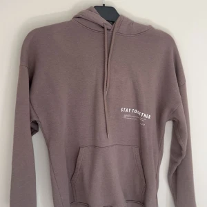 grå/brun hoodie med tryck Stay Together - Säljer en ljusbrun hoodie med vit text 'STAY TOGETHER' på framsidan och en lista med storstäder på ryggen.🩷