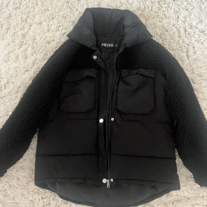 Svart pufferjacka från Pieces  - Säljer en svart pufferjacka från Pieces i storlek S. Jackan har fluffiga teddyärmar, två stora bröstfickor och hög krage. Stängs med dragkedja och tryckknappar. Perfekt för kalla dagar.