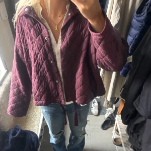 Quiltad vinröd jacka - Säljer en quiltad jacka i vinröd färg med snygg loose passform och knytband nedtill. Jackan har tryckknappar framtill och ett rutigt mönster i tyget. Jackan är från Zara och enbart använd fåtal gånger. Den är i storlek xs/s men passar också M. Skriv för fler bilder och kan gå ner i pris vid en snabb affär!♥️💖