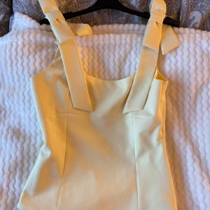 Gul topp från Zara - Supersöt ljusgul linnetopp från Zara med breda axelband som knyts i rosett. Toppen har en figurnära passform och är perfekt för att ge din outfit en fräsch och somrig vibe. Materialet känns mjukt och lätt mot huden.