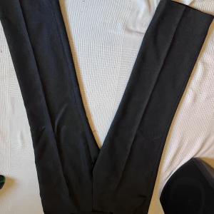 Svarta kostymbyxor från Barg E Sabz - Snygga svarta kostymbyxor från Barc E Sabz i klassisk rak modell. Byxorna har en stilren look med pressveck och är tillverkade i ett mjukt material som ger en skön känsla. Perfekta för dig som gillar en clean och dressad stil.