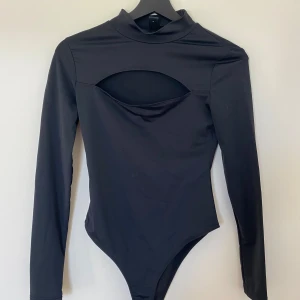 Svart långärmad body  - Svart body i storlek S med lång ärm och cut-out. Toppens material är mjukt och stretchigt