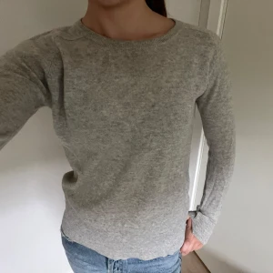 Grå stickad soft goat - Snygg grå stickad soft goat i Kashmir med ett litet hål på ena armbågen man kan sy