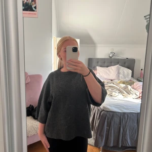 Mörkgrå stickad tröja med trekvartsärm - Säljer en mörkgrå stickad tröja med rund hals och trekvartsärmar. Tröjan har en loose passform och är supermjuk, perfekt för att chilla eller hänga med kompisar. Enkel och stilren design som funkar till jeans eller leggings.