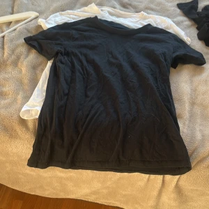 Svart och vit basic t-shirt duo - Två klassiska t-shirts i svart och vitt, båda med rund hals och korta ärmar. Perfekt för dig som gillar enkel och clean stil. Materialet känns mjukt och lätt, troligtvis bomull. Passformen är normal och de har en rak siluett.