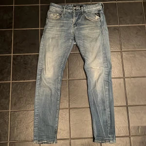 Replay ljusblå jeans, storlek 30/32 - Säljer ett par snygga ljusblå jeans från Replay i storlek 30/32. De har klassisk femficksdesign, coola slitningar och raka ben med smal passform. Jeansen är tillverkade i mjukt denim och har Replay-logga på bakfickan. Perfekt för dig som är grisch och som vill ha en stilren look.