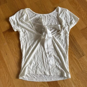 Vit topp med rosett och öppen rygg - super söt vit t-shirt med rosett och öppen rygg 💕 kolla gärna in min profil för bundle!🥰