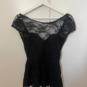Peplumtopp/blus - Elegant svart blus/peplum från Gina Tricot med  spetsdetalj och blommigt mönster. Köpt second hand och är i använt skick men inte defekter förutom lite trådar som hänger ut.