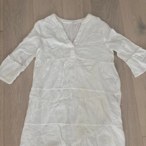 Vit sommarklänning från ONLY XS - Supersöt vit klänning från ONLY i storlek XS. Den har v-ringad hals, trekvartsärmar med volangdetalj och är gjord i mjuk bomull. Perfekt för varma dagar med sin luftiga och sköna känsla. Enkel och stilren design som är lätt att matcha med accessoarer.