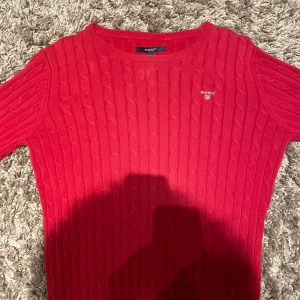 GANT Cotton Cable C-Neck – Röd stickad tröja - Klassisk stickad tröja från GANT i mjuk bomull. Rund hals, tidlöst cablemönster och diskret logga på bröstet. Fungerar lika bra till vardags som mer uppklätt. Skriv med ägare innan köp!