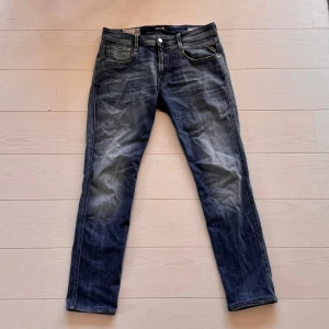 Replay Anbass blå jeans slim fit - Säljer ett par Replay Anbass jeans i klassisk blå tvätt med snygga slitningar och raka ben. Jeansen har fem fickor, dragkedja och knappstängning samt Replay-logga på bakfickan. Perfekt passform och cool faded look. Storleken var 32/34 men benen har blivit uppsydda till 32/32