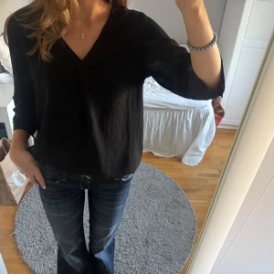 Svart v-ringad blus från Jdy - Säljer en svart blus från jdy med v-ringad hals och trekvartsärm. Blusen har en loose passform och är gjord i ett mjukt, tunt material. Perfekt att matcha med jeans eller kjol för en chill och stilren look.🩶🤍