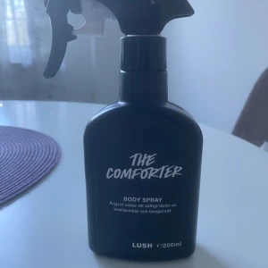 Lush The Comforter Body Spray 200ml - The Comforter Body Spray från Lush. Doften har inslag av svarta vinbär och bergamott, vilket ger en fruktig och fräsch vibe. Flaskan rymmer 200 ml, se sista bilden för mängd 🫶🏼