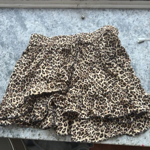 Leopardmönstrad volangkjol Luca & Ola - Supersnygg kort kjol från Luca & Ola med leopardmönster i beige och bruna toner. Kjolen har flera volanger som ger en cool och livlig look. Perfekt för dig som vill sticka ut med ett djuriskt print och skön passform. De är en kjol och en tröja passar alla storlekar