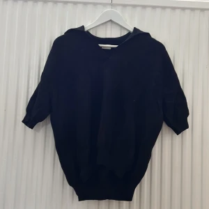 Svart stickad tröja från Stories - Svart stickad tröja från Stories i storlek S. Tröjan har kortare ärmar och en avslappnad passform med v-ringad hals. Perfekt för lager-på-lager och enkel att matcha med olika outfits.