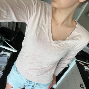 Ljusrosa v-ringad tröja - Säljer en ljusrosa v-ringad tröja i mjukt material. Tröjan har långa ärmar och ribbade muddar vid ärmslut och nederkant. Perfekt för dig som gillar en enkel och stilren look.