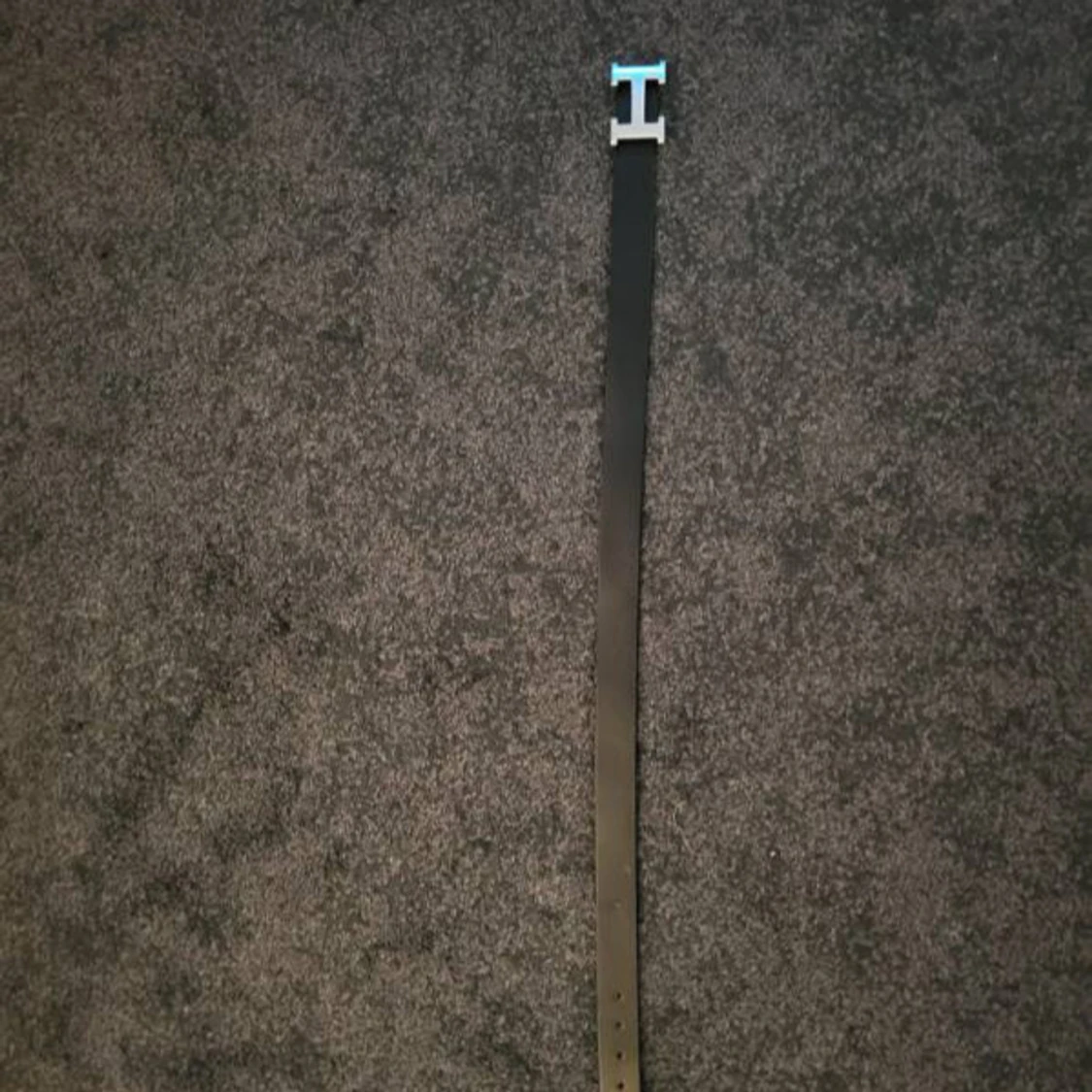 Svart bälte med silverfärgat H-spänne