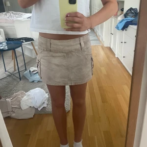 Minikjol cargo - Beige/brun/grå minikjol med cargofickor på sidorna och dragkedja bak. Aldrig använd! Storlek S